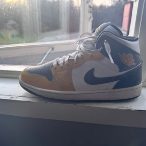 Nike Air Jordan 1 Mid Yellow Ochre - Nike Air Jordan 1 Mid sneakers. Klassisk hög siluett med snörning, perforerad tå och ikonisk Swoosh på sidan. Skon är tillverkad i skinn och har en platt sula för skön komfort. Nypris: 2 499kr