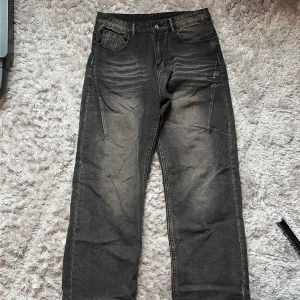 Svarta jeansbyxor i straight fit - Svarta jeansbyxor i straight fit med slitna detaljer och ljusare partier framtill och baktill. Klassisk femficksmodell med bälteshällor och knappgylf. Perfekta för en avslappnad och cool look. Knappt använda.
