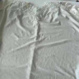 Vit spetsklänning från Amisu - Supersöt vit klänning från Amisu med tunna axelband och vacker spetsdetalj upptill. Klänningen har en slät, mjuk yta och är perfekt för sommarens alla tillfällen. Enkel och stilren design som känns både fräsch och trendig.