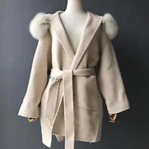 Beige kappa med fluffig huva och bälte - Säljer min ljusbeige Viva Nilla-kappa med stor fluffig huva i vitt och matchande bälte i midjan. Omlottmodell med långa ärmar och loose passform. Köpt för 3000 kr och använd ett fåtal gånger – fortfarande i fint skick. Perfekt för dig som vill ha en mysig men ändå stilren och festlig look under höst och vinter! OBS: bilderna är lånade, men skriv gärna om ni vill se mina egna bilder !