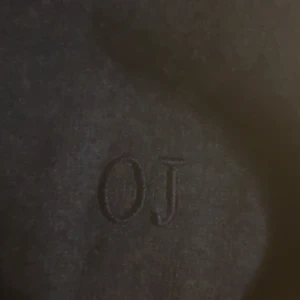 Mörkblå stickad tröja från OJ - Mörkblå stickad tröja från OJ med broderad logga på bröstet. Klassisk modell med rund hals och långa ärmar, perfekt för lager-på-lager under kyliga dagar. Enkel och stilren design som funkar till det mesta.