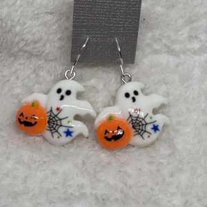 Halloween örhängen med spöken och pumpor - Unika örhängen med vita spöken och orange pumpor, dekorerade med svarta spindelnät och färgglada stjärnor. Perfekta för Halloween och höst, dessa örhängen har en lekfull design som sticker ut och ger din outfit extra edge.