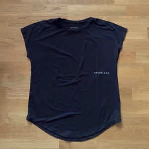 Svart t-shirt från Röhnisch - Svart t-shirt från Röhnisch med diskret logga på bröstet. Modellen är klassisk med rund hals och korta ärmar. Materialet är mjukt och lätt. 