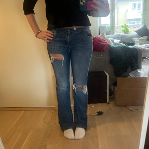 Blå bootcut jeans från Trussardi - Säljer ett par blå bootcut jeans från Trussardi med slitna detaljer och hål vid knäna. Jeansen har klassisk femficksdesign, normal passform och är tillverkade i jeansmaterial. Perfekta för dig som gillar en avslappnad och trendig look. Jeansen är i storlek 28/42, skulle säga att dom passar nån som vanligt vis bär S!!❣️❣️
