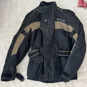 MC-ställ Bering stl S - Svart MC-ställ, jacka och byxor från Bering med förstärkta partier och dragkedjor vid fickorna. Byxorna är tillverkade i slitstarkt syntetmaterial och har justerbar midja samt resår vid benslut. Perfekta för dig som vill ha skydd och komfort på motorcykeln. Jackan har skydd i axlar och armar (ej inbyggt ryggskydd) justerbar midja. Fodrat med möjlighet att ta bort fodret.  Mycket gott skick, använt av kvinna två säsonger. 