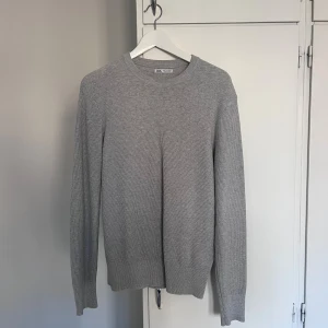 Grå stickad tröja från Zara - En stilren grå stickad tröja från Zara i storlek S. Tröjan har rund halsringning, ribbade muddar och lång ärm. 