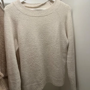 Krämvit stickad tröja med rund hals - Mysig krämvit stickad tröja med rund halsringning och ribbade muddar vid ärmslut och nederkant. Perfekt för lager-på-lager och passar till allt. Långärmad och enkel att matcha med både jeans och kjol.