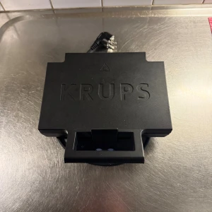Krups Smörgåsgrill - Smörgåsgrill från Krups i svart utförande. Plattorna är rena och i gott skick, perfekt för att göra två smörgåsar samtidigt. Enkel att använda med tydliga indikatorer. Inga synliga defekter eller slitage. Passar utmärkt i köket för snabba och goda varma mackor.