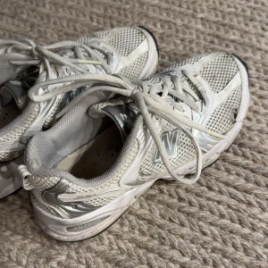 Vita New Balance sneakers mesh - New Balance sneakers i vitt och silver. Dem har hål på ena sidan men går att fixa hos en skomakare. 