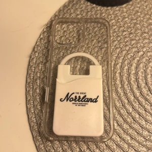 Apple iPhone MagSafe Skal med The Great Norrland korthållare - Transparent MagSafe-skal för iPhone med integrerad The Great Norrland korthållare. Skalet är designat av Apple och passar MagSafe-tillbehör. Mindre repor och smuts syns, men i gott skick. Perfekt för dig som vill kombinera skydd och praktisk korthållare.