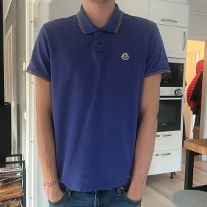 Blå pikétröja från Moncler - Snygg blå pikétröja från Moncler med klassisk krage och knäppning framtill. Skriv för frågor och pris kan diskuteras!