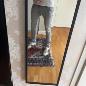 Jacob Cohën ljusgrå Nick Slim jeans - Säljer ett par ljusgrå jeans från Jacob Cohën, modell Nick Slim. Jeansen har en slim passform, klassisk femficksdesign och JC-broderi på fickan. Tillverkade i mjukt bomullstyg med snygga detaljer och läderpatch bak. Perfekta för dig som gillar stilrena och moderna jeans.