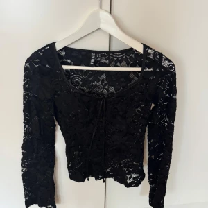 Svart spetsblus från Pieces XS - Säljer en svart långärmad blus från Pieces i storlek XS. Blusen är helt i spets med blommigt mönster och har en snygg knytning framtill. Använt enstaka gång, är i nyskick! Köpt på Vero Moda 