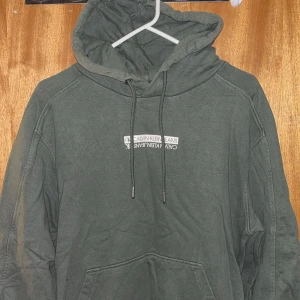 Grön hoodie från Calvin Klein Jeans - Snygg grön hoodie från Calvin Klein Jeans med vit logga framtill. Tröjan har huva med snörning och en stor magficka. Perfekt för dig som gillar en avslappnad och trendig stil.