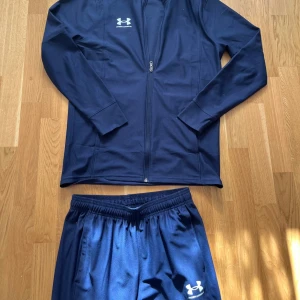 Under armour dress  - Snygga marinblå träningsbyxor från Under Armour med elastisk midja och vita logotypdetaljer. Byxorna har en rak passform, sidofickor och är gjorda i ett mjukt syntetmaterial som andas. Perfekta för gymmet eller sportaktiviteter.storlek S inga defekter. Sjukt snygg 