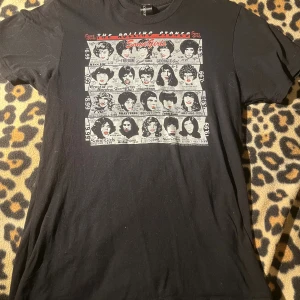 Rolling Stones Some Girls t-shirt svart - Svart t-shirt från Sourpuss med Rolling Stones Some Girls-tryck i vitt och rött framtill. Klassisk passform med rund hals och korta ärmar. Trycket har retroinspirerat motiv med olika frisyrer och text. Perfekt för dig som gillar bandmerch och vintage vibes.