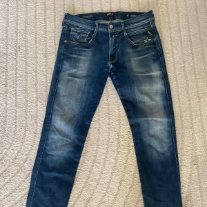 Replay Anbass jeans blå, stl 31/32 - Snygga Replay Anbass jeans i blå tvätt med slitningar och klassiska bakfickor. Modellen har smal passform och raka ben. Jeansen är gjorda i stretchig denim för extra komfort och har detaljerade sömmar och dragkedja i gylfen. Säljer dom eftersom att dom har ett hål mellan benen. Så dessa är för den som är villig att laga dom😁 storlek 31/32