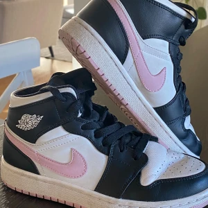 Nike Air Jordan 1 svart/vit/rosa - Säljer ett par Nike Air Jordan 1 sneakers i storlek 35,5 med svart och vit ovandel i skinn och rosa detaljer. Väldigt bekväma och sköna! Sparsamt använda och fina. Dessa ligger ute för ca 3000 kr just nu men pris kan diskuteras vid snabb affär! 