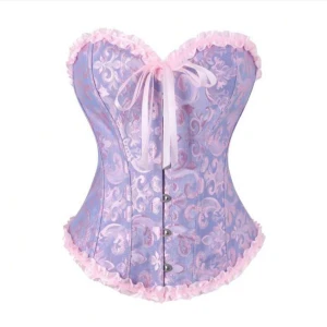 Lila och rosa korsett - Superfin korsett i lila med ljusrosa mönster och volangkant från shein. Framtill finns en söt rosett och knäppning med metallhakar. Passar perfekt nu till halloween. Helt ny inte ens uttagen ur förpackningen. Jag säljer då jag råkade köpa två. Köpt för 100kr och priset kan förhandlas