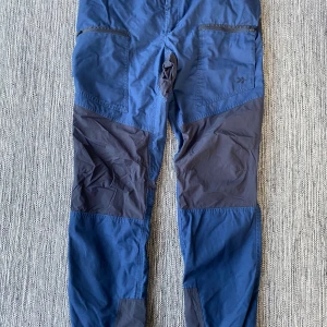 Blå funktionsbyxor Lager 157 X-Large - Säljer ett par blå funktionsbyxor från Lager 157, modell Vindeln. Byxorna har mörkare blå förstärkningar på knän och bak, praktiska fickor med dragkedja och är tillverkade i slitstarkt syntetmaterial. Perfekta för utomhusaktiviteter och äventyr.
