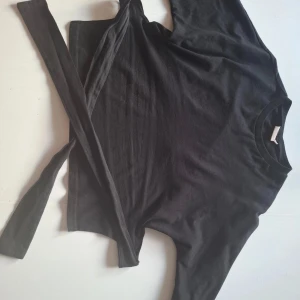 Svart tröja med knytband - Säljer en svart tishirt med öppenrygg och knytband från Nelly. Säljer då jag vill ha en storlek större. Pris kan diskuteras vid snabba köp💓