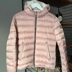 Ljusrosa pufferjacka från Colmar - Säljer min systers ljusrosa pufferjacka från Colmar med huva och dragkedja framtill. Jackan har två fickor med dragkedja och ett diskret logomärke på ärmen. Perfekt för kyliga dagar och ger en trendig look med sin quiltade design. Nypris:4599Kr Mitt pris:1499