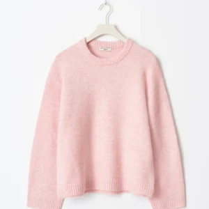 Ljusrosa stickad tröja från Gina - Supermjuk ljusrosa stickad tröja från Gina, med rund halsringning och ribbade muddar. Tröjan har en loose passform och långa ärmar, perfekt för att mysa i under kyliga dagar. Aldrig använd