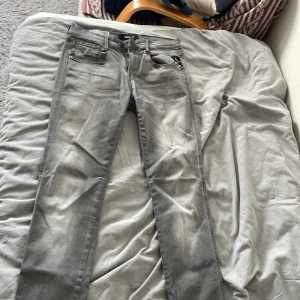 Replay Anbass Hyperflex grå jeans - Snygga Replay Anbass Hyperflex jeans i grått med slim passform. Modellen har klassisk femficksdesign, svarta detaljer och stretchigt material som sitter skönt. Perfekt för dig som gillar stilrena och moderna jeans med smal siluett. Skriv gärna om du har frågor 🤗