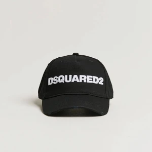  Dsquared2 keps - Svart keps från Dsquared2 med vit broderad logga framtill och texten 'DEAN & DAN CATEN' baktill. Klassisk böjd skärm och justerbart spänne i metall bak. Tillverkad i bomull för en skön och snygg look. KVITTO FINNS! nypris 1500kr, mitt pris 600kr 