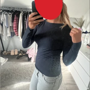 Mörkblå långärmad topp - Säljer en mörkblå långärmad topp med tight passform och rund halsringning. Enkel och stilren design som passar perfekt till jeans eller kjol. Materialet känns mjukt och stretchigt mot huden.