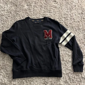 Svart sweatshirt Morris - Svart sweatshirt från Morris R Club med stor röd M-patch på bröstet och två vita ränder på ena ärmen. Hör av dig vid frågor eller prisförslag🙌