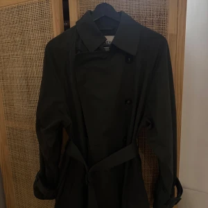 Mörkgrön trenchcoat - Mörkgrön trenchcoat från ZARA med dubbelknäppning och krage. Jackan har långa ärmar, två sidfickor och en snygg detalj i ryggen. Använd några fåtal gånger, fint skick. 