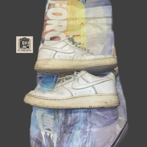 Nike Air Force 1 Anniversary Edition - Vita Nike Air Force 1 Anniversary Edition sneakers med låg profil och rund tå. Skorna har snörning och är tillverkade i skinn med vit sula och diskreta Nike-loggor på hälen och tungan. Perfekt för dig som gillar tidlös streetstyle. Ganska slitna därav priset! 