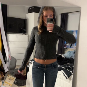 Mörkgrå stickad hoodie  - Säljer en mörkgrå stickad hoodie från 157 med ribbad struktur och dragkedja framtill. Tröjan har huva och långa ärmar, perfekt för dig som gillar en chill och trendig look. Materialet är stickat och känns mjukt mot huden.