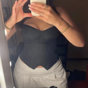 Svart, randig korsett - Svart, randig korsett som har en tydlig bygel. Fin till många olika tillfällen, använd en gång. Har dragkedja och knytning i ryggen för och är lätt att anpassa efter önskemål