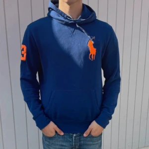 Blå Chief Keef hoodie från Ralph Lauren - Säljer en marinblå hoodie från Ralph Lauren med stor orange logga på bröstet och siffra 3 på ärmen. Tröjan har huva med snörning och en klassisk känguruficka. Elastisk midja ✅ Unik hoodie där av de höga priset men kan diskuteras ✅ 170-177 som bäst