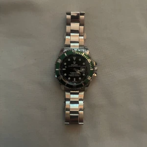 Klocka - En fin klocka som är använd ett fåtal gånger, har en svart urtavla med grönt runtomkring. Skicket på klockan är 10/10. Perfekt för en stilren look. 