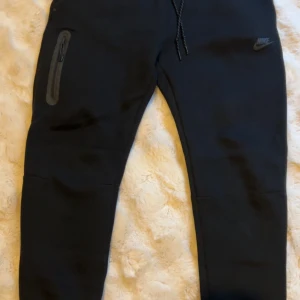 Svarta Nike tech byxor ny modell - Svarta mjukisbyxor från Nike. Köptes nyligen men knappt använd. Köptes för 1250kr från Jd men den är i nyskick
