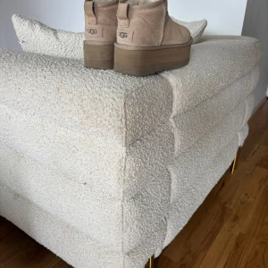 Beige UGG boots med plattform - Säljer ett par beige UGG boots med plattformsula och rund tå. Skorna är tillverkade i mjuk mocka med fluffigt foder på insidan för extra komfort. De har en rejäl brun sula som ger höjd och en cool look. Perfekta för dig som gillar chunky boots och vill ha något varmt och stilrent.