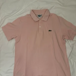 Ljusrosa pikétröja från Lacoste, - Säljer en klassisk ljusrosa pikétröja från Lacostet. Priset kan diskuteras då jag försöker att bli av med så mycket som möjligt 