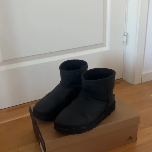 Svarta UGG boots med fårskinn - Säljer ett par klassiska svarta UGG boots i skinn med mjukt och varmt foder av fårskinn. Modellen har rund tå, platt sula och UGG-logga baktill. Perfekta för kalla dagar och har en enkel, stilren look som funkar till det mesta. Använda 1 säsong så i väldigt fint skick och kommer tvätta skorna innan postningen! Tyvärr finns inte Box eller så kvar:( 