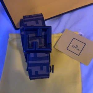 Svart och grått Fendi bälte med FF-mönster - Säljer ett snyggt Fendi bälte med ikoniskt FF-mönster i svart och grått. Bältet har en stilren, fyrkantig spänne i svart och är tillverkat i skinn. Perfekt accessoar för att lyfta din outfit med en lyxig touch från Fendi.