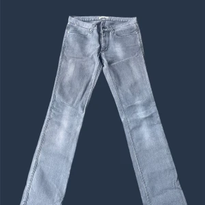 Grå jeans från Acne Studios - Säljer ett par grå jeans från Acne Studios med klassisk femficksdesign och raka ben. Jeansen har en snygg tvättad look och subtila slitningar. Perfekta för dig som gillar stilrena och tidlösa plagg. Materialet är mjukt och följsamt jeans.