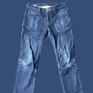Acne Studios blå jeans 29/32 - Snygga blå jeans från Acne Studios i klassisk femficksmodell. Jeansen har raka ben, normal passform och är tillverkade i slitstarkt denim. Fina kontrastsömmar och diskret tvättad look. Perfekta för dig som gillar stilrena och tidlösa jeans.