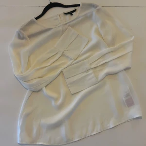 Vit blus med breda manschetter från Veromoda - Säljer en stilren vit blus från Veromoda med rund halsringning och breda manschetter med knappdetalj. Blusen har långa ärmar och är gjord i ett mjukt, lätt material som ger en snygg flowy känsla. Perfekt för dig som gillar minimalistisk och clean stil.