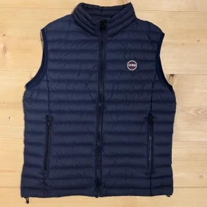 Mörkblå dunväst från Colmar - Snygg mörkblå dunväst från Colmar. Västen har två praktiska fickor med dragkedja och Colmar-logga på bröstet. Perfekt att slänga över en hoodie för extra värme eller för ett extra lager. Bara att ställa frågor om du undrar något! Skick: 9/10. Storlek: 48 (passar S). Priset är inte hugget i sten!