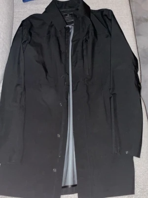 Svart klassisk rock från Berkeley - Säljer en svart klassisk rock från Berkeley, modell Carmel Classic Coat. Rak passform med krage, diskreta knappar och dragkedja vid bröstfickan. Snygg och stilren design som funkar till allt. Materialet är polyester och jackan har långa ärmar. Bilden från Google är inte exakt den utan ungefär! 