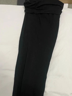 Svarta mjukisbyxor med hög midja - Säljer ett par svarta mjukisbyxor med hög midja och bred linning. Byxorna är i mjukt och stretchigt material, perfekta för chill eller träning. De har en enkel och clean look utan synliga detaljer eller mönster.