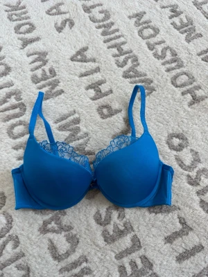 Blå spets-bh från Lounge - Snygg blå bh från Lounge med vadderade kupor och broderad spetsdetalj upptill. Axelbanden är justerbara och har Lounge-loggan invävd. Tillverkad i polyamid och elastan för en bekväm passform.