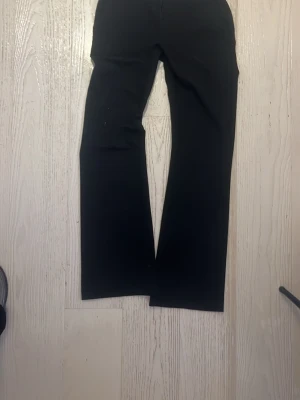 Svarta kostymbyxor från Lindex - Snygga svarta kostymbyxor från Lindex med raka ben och klassisk passform. Byxorna har bälteshällor, diskreta fickor bak och dragkedja fram. Perfekta till en stilren look och passar till både skjorta och t-shirt.